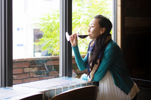 窓際でワインをたしなむ女性の写真